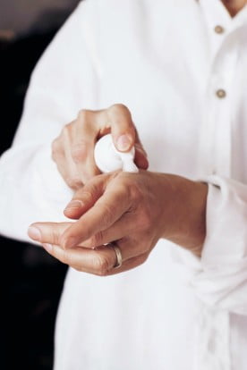 A close up photo of a woman's hands applying moisturizing cream to her hands.