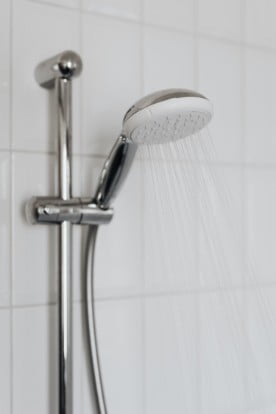 A close up photo of a bathroom shower head with with water coming out of it. 
