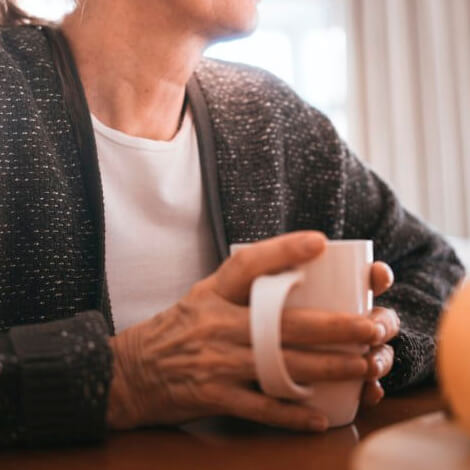 An elderly woman enjoying a warm cup of coffee.
