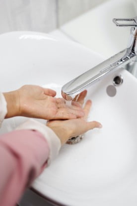 Close up of a woman's arms, washing her hands in a sink.