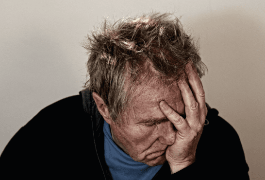 A man feeling overwhelmed, holding his head in his hands, possibly due toA man feeling overwhelmed, holding his head in his hands, possibly due to stress or frustration. stress or frustration.