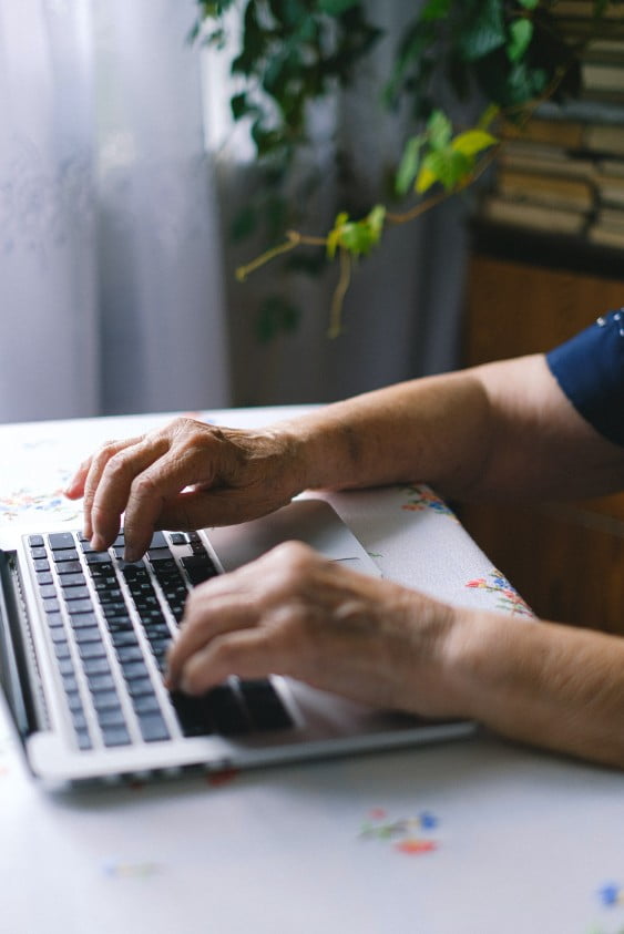 A womans arms focused on her work, typing on a laptop computer.